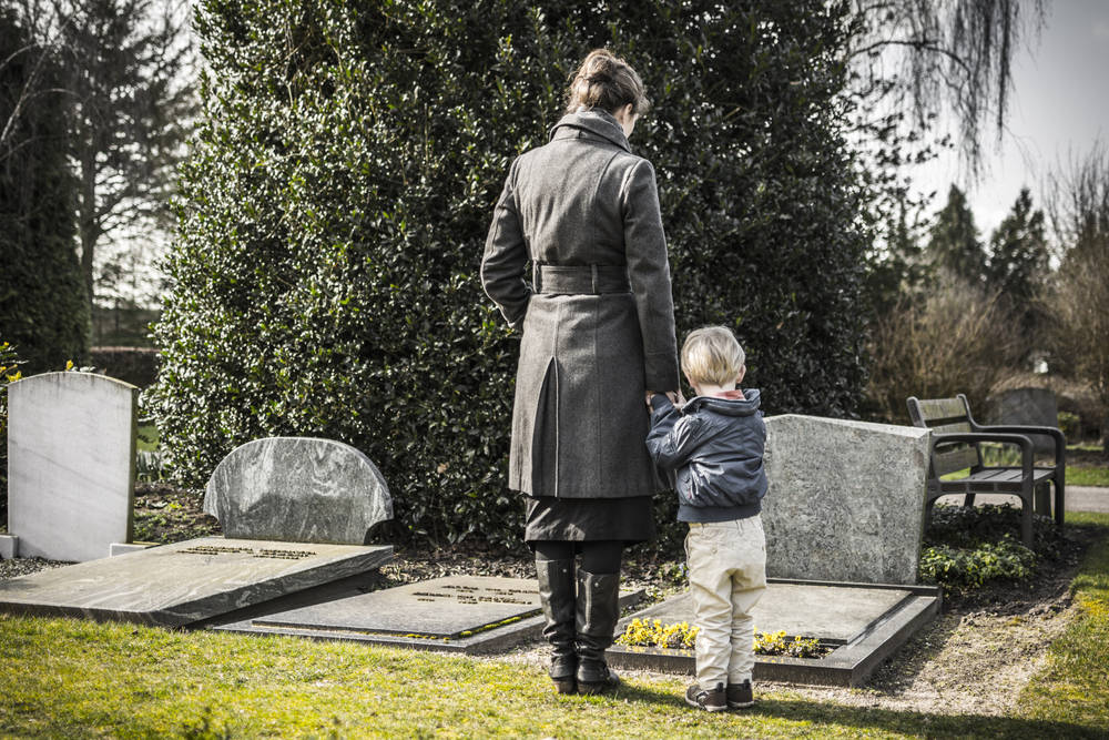 Woman and child standing by grave in mourning