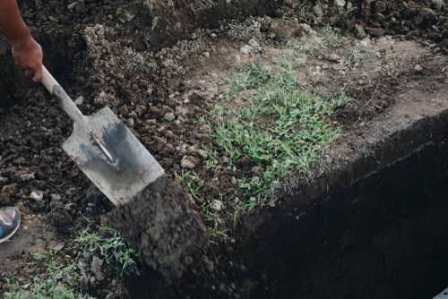 person moving dirt into grave