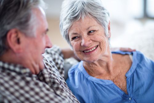 elderly man and woman talking on couch